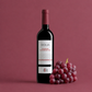 Dolia Cannonau red wine bottle with fresh red grapes on a deep red background, Sardinian wine by Cantina di Dolianova
