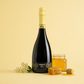 Càralis Malvasia demi sec sparkling wine bottle with honey jar and honeycomb on a golden background