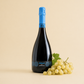 Càralis Vermentino brut sparkling wine bottle with fresh white grapes on a light background