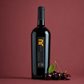 Jù Isola dei Nuraghi Sardinian red wine bottle with fresh cherries on a deep red background