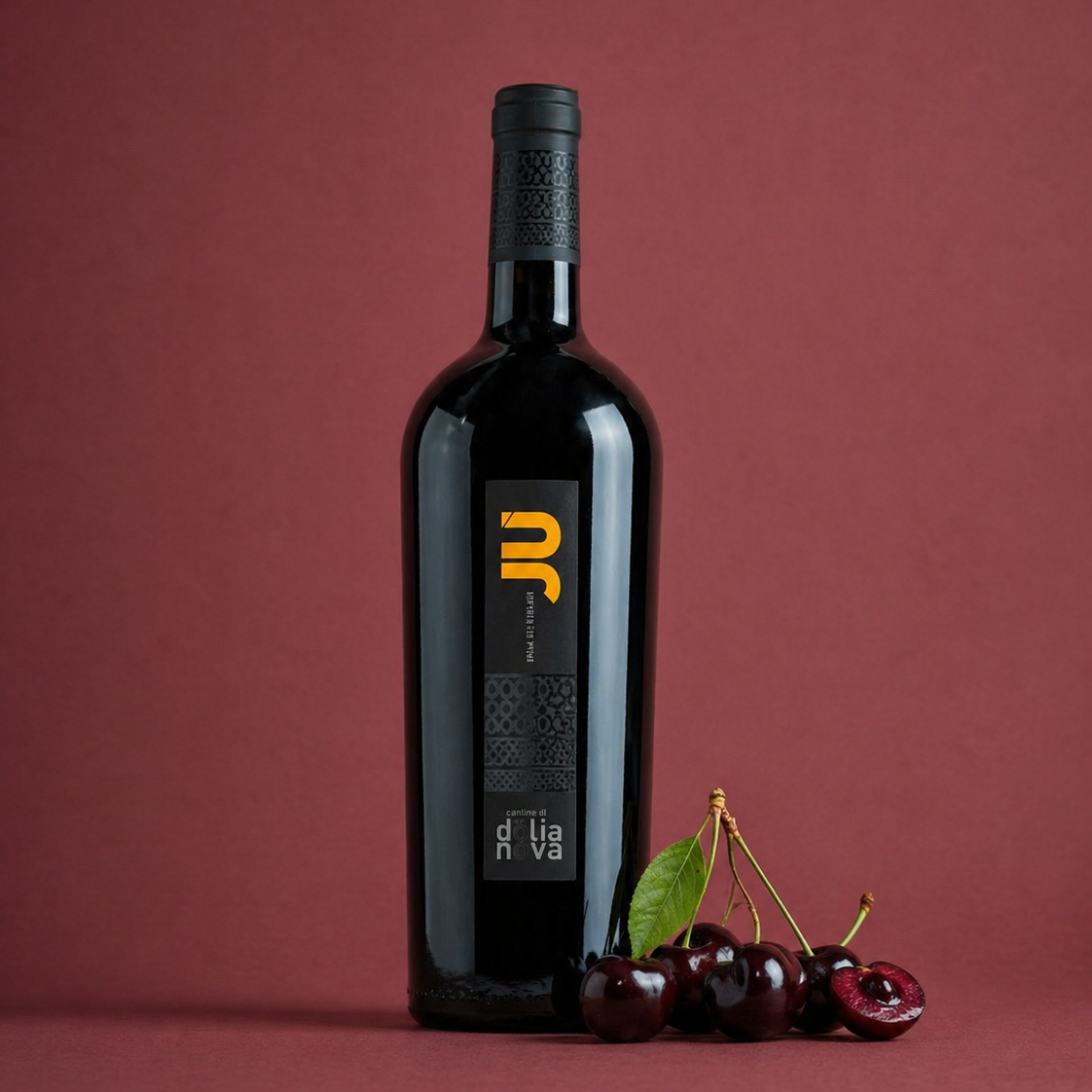 Jù Isola dei Nuraghi Sardinian red wine bottle with fresh cherries on a deep red background