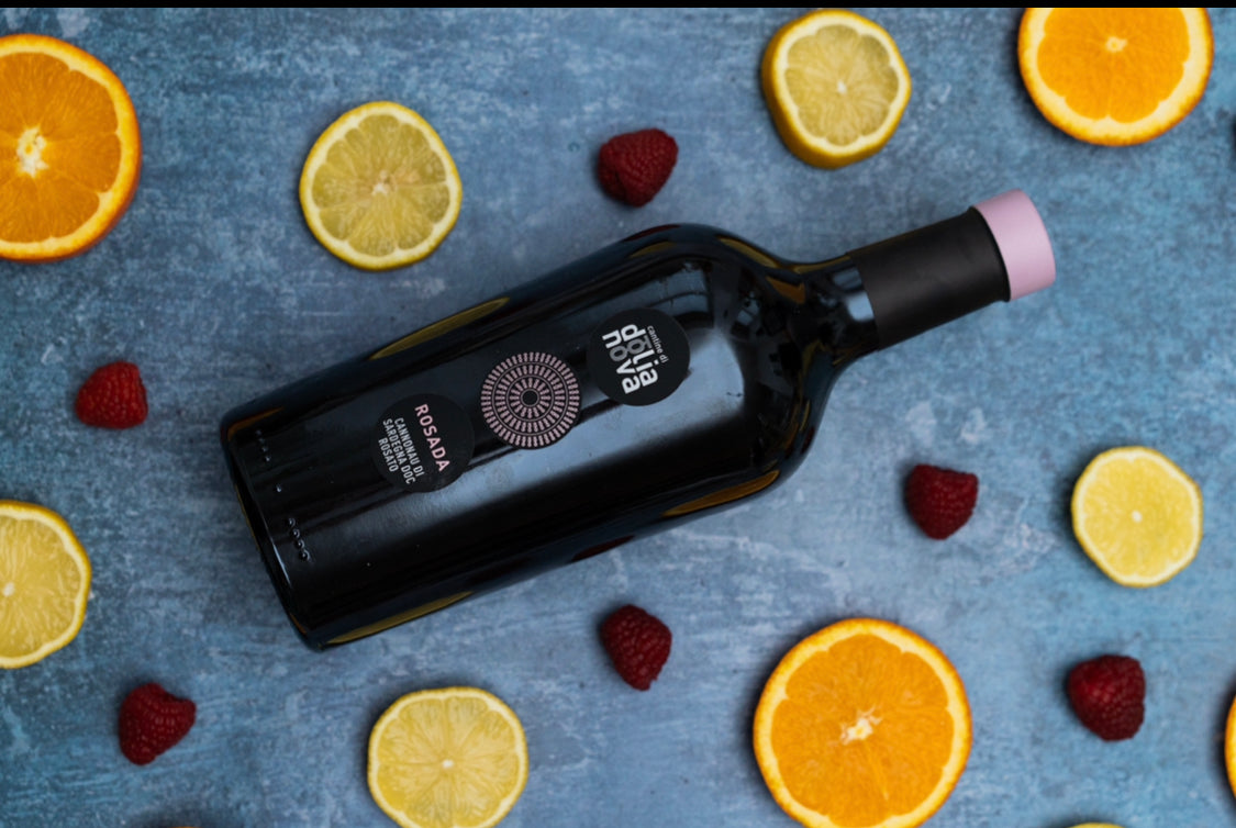 Rosada Cannonau di Sardegna DOC rosé wine bottle with citrus slices and raspberries